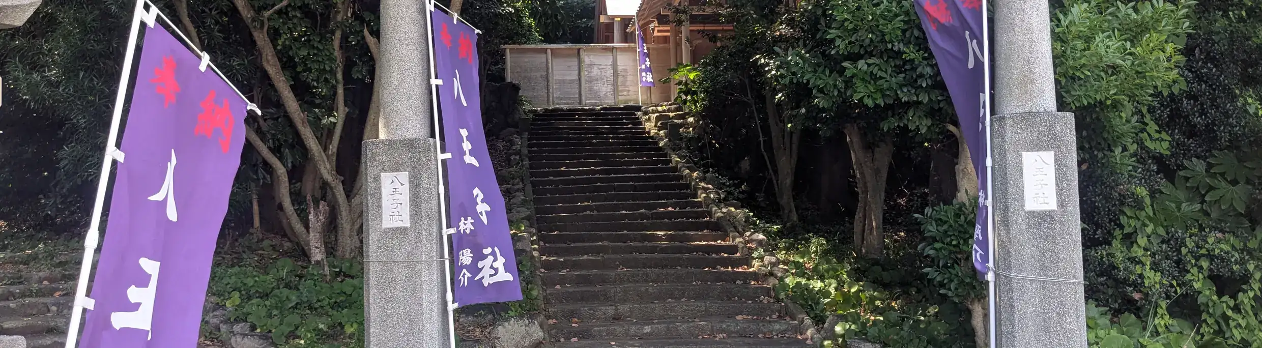 八王子社の鳥居と参道の石段。紫の幟が立つ
